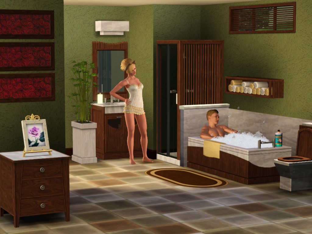 A woman with blonde hair in a towel stands next to a bathtub with a person relaxing inside, within a master bedroom and bathroom featuring green walls, wooden furnishings, and rolled towels on a wall-mounted shelf.